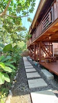 Una terraza de madera con un sendero de piedra que lleva a un edificio con balcón.
