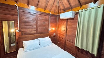 Habitación de madera con una cama, un espejo y un equipo de aire acondicionado.
