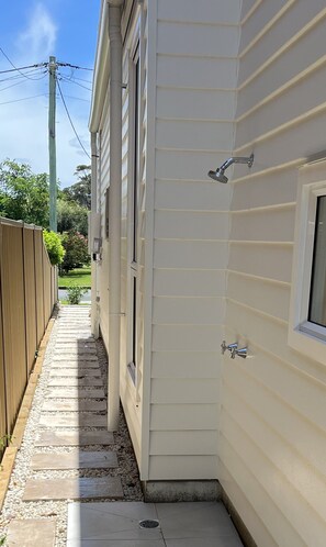 A narrow pathway leading to a white house with a wooden fence on one side and a window on the other. - Modern beach house - 1 min walk to beach (Currarong)