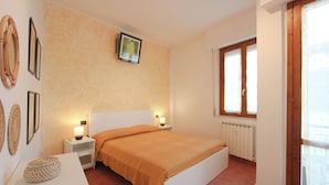 A bedroom with a bed, nightstands, a wall-mounted picture, and a window with curtains. - Pratovecchio Suite (Florence)