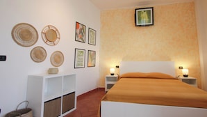A bedroom with a bed, two bedside tables with lamps, a white shelving unit, and wall-mounted artwork. - Pratovecchio Suite (Florence)