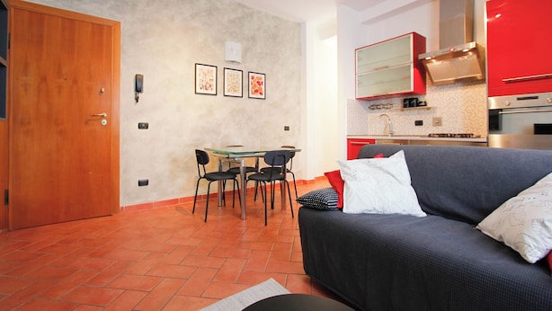 A compact living space with a dining area, kitchenette, and a sofa with pillows. - Pratovecchio Suite (Florence)