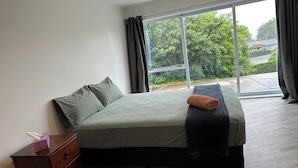 A bedroom with a bed, a wooden dresser, and a window with curtains. - Rotorua Studio in a peaceful location. (Rotorua)