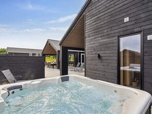 A hot tub outside a building with a covered patio area.