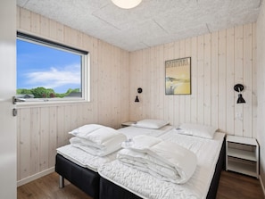 Une chambre avec un grand lit, une fenêtre et un tableau représentant le Danemark accroché au mur.