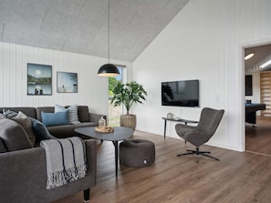 Una sala moderna con un sofá, un sillón, una mesa de centro y un televisor.
