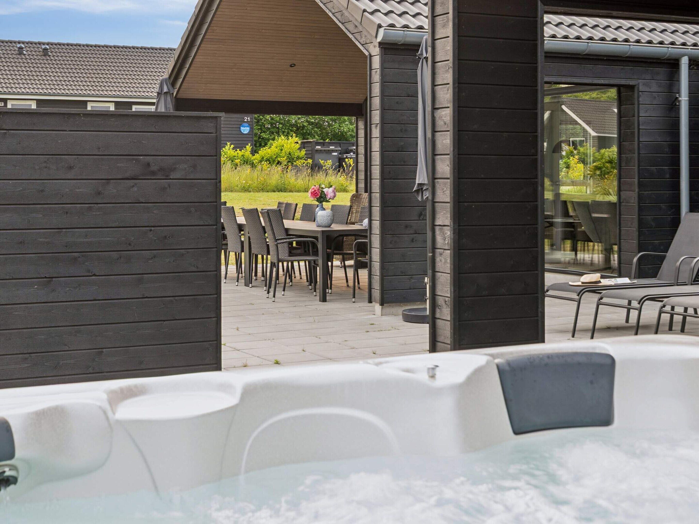 A spa area with a hot tub, outdoor seating, and a view of the surrounding garden.