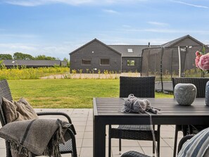 An outdoor patio area with a table, chairs, and a decorative vase.