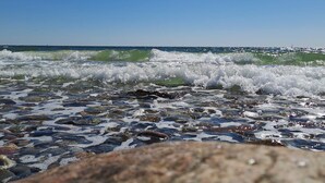 Een strand met golven, heldere lucht en een verre horizon.