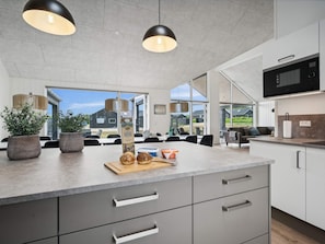 Una cocina moderna con una isla grande, electrodomésticos integrados y vistas al exterior.