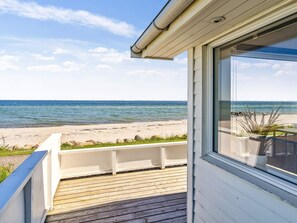 A wooden deck leading to a beach view with a clear sky. - 6 Person Holiday Home in Otterup (Otterup)