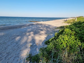 A beach with a clear sky, calm sea, and some vegetation. - 6 Person Holiday Home in Otterup (Otterup)