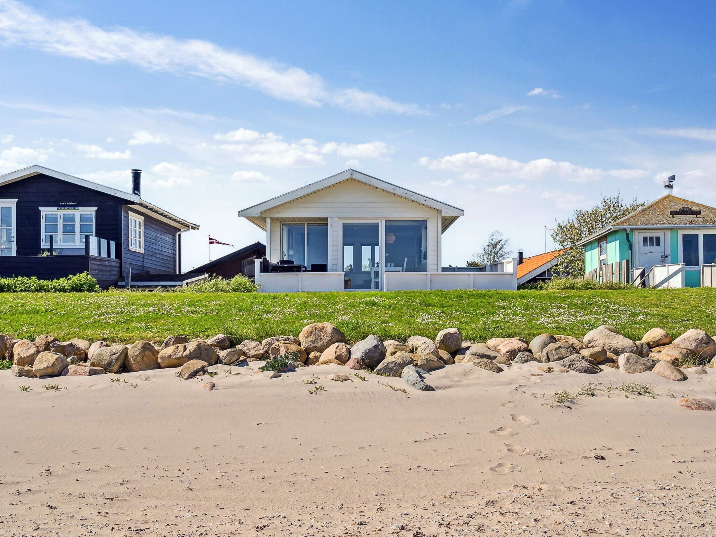 Una propiedad frente al mar con una casa moderna, ventanas amplias y un porche cubierto.