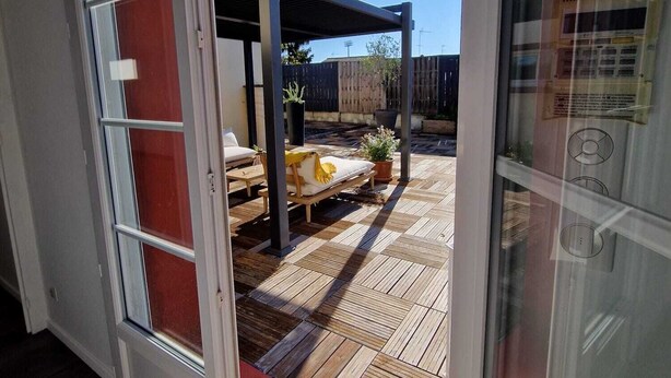 Moderni patio, jossa on puinen terassi, ulkokalusteet ja pergola.