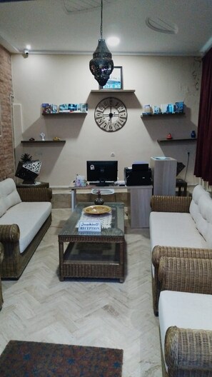 A living room with two sofas, a coffee table, a TV, and shelves with books. - golden twilight (Imsouane)