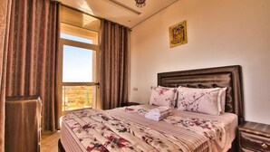 Una camera d'albergo con un letto grande, vista dalla finestra e un lampadario.