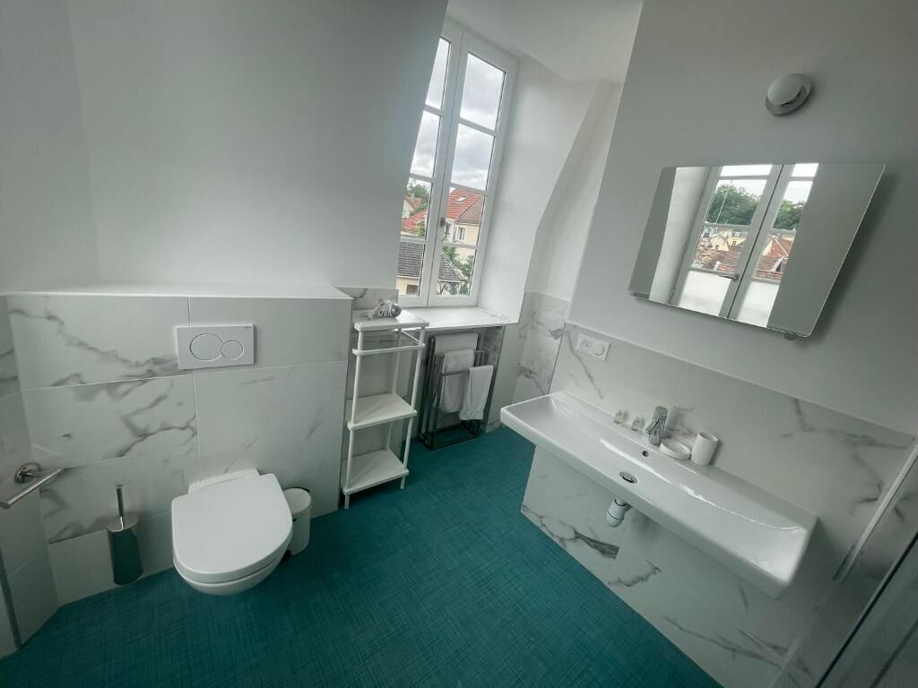 A modern bathroom with a toilet, sink, and shelves.
