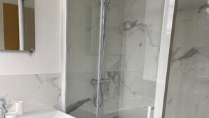 A modern bathroom with a glass-enclosed shower, a white sink, and a marble-tiled wall. - IL MAESTRO - HOTEL RESTAURANT DU CHATEAU (Ecouen)