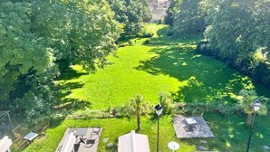 A lush green garden with a wooden deck and chairs, surrounded by dense trees. - IL MAESTRO - HOTEL RESTAURANT DU CHATEAU (Ecouen)