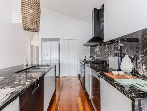Una cucina moderna con piano di lavoro in marmo, elettrodomestici in acciaio inossidabile e pavimento in legno.