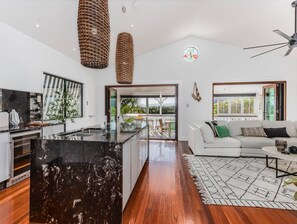 A modern kitchen with a black marble island, a white sofa with a patterned rug, and a ceiling fan.