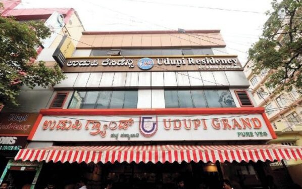 A building with signage for Udupi Residency and Udupi Grand. - Hotel Udupi Residency Koramanagala (Bengaluru)