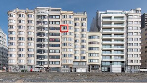 Un edificio residenziale a più piani con balconi, situato vicino a una spiaggia sabbiosa.