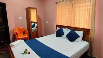 Habitación de hotel con cama, ventilador de techo, unidad de aire acondicionado, espejo y ventana con cortinas.