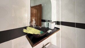 Un baño con un espejo, una estantería de madera con artículos de aseo y una pared con diseño.