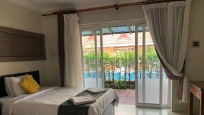 Habitación de hotel con dos camas, vista a una piscina y puerta corrediza al exterior.