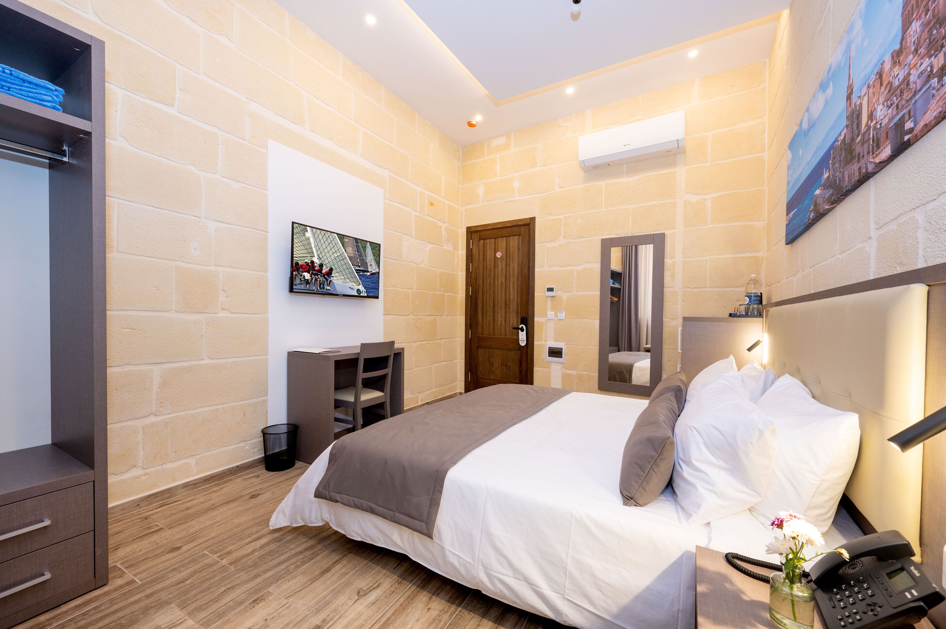 Habitación de hotel con una cama grande, un escritorio, una silla y un armario.