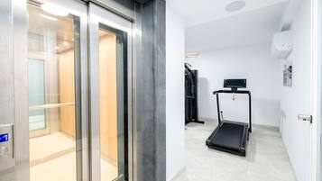 Een lift met glazen deuren, een loopband en een wandairconditioner in een modern interieur.