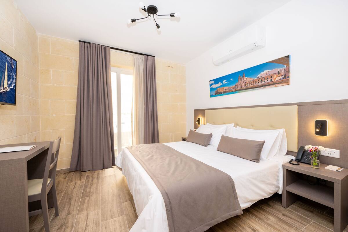 Una habitación de hotel con cama, mesita de noche, escritorio y silla.