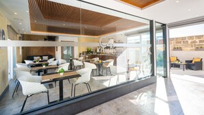 A modern interior with a dining area, kitchen, and a glass wall offering a view of the outdoors. - C4 Retreats Gozo (Xaghra)