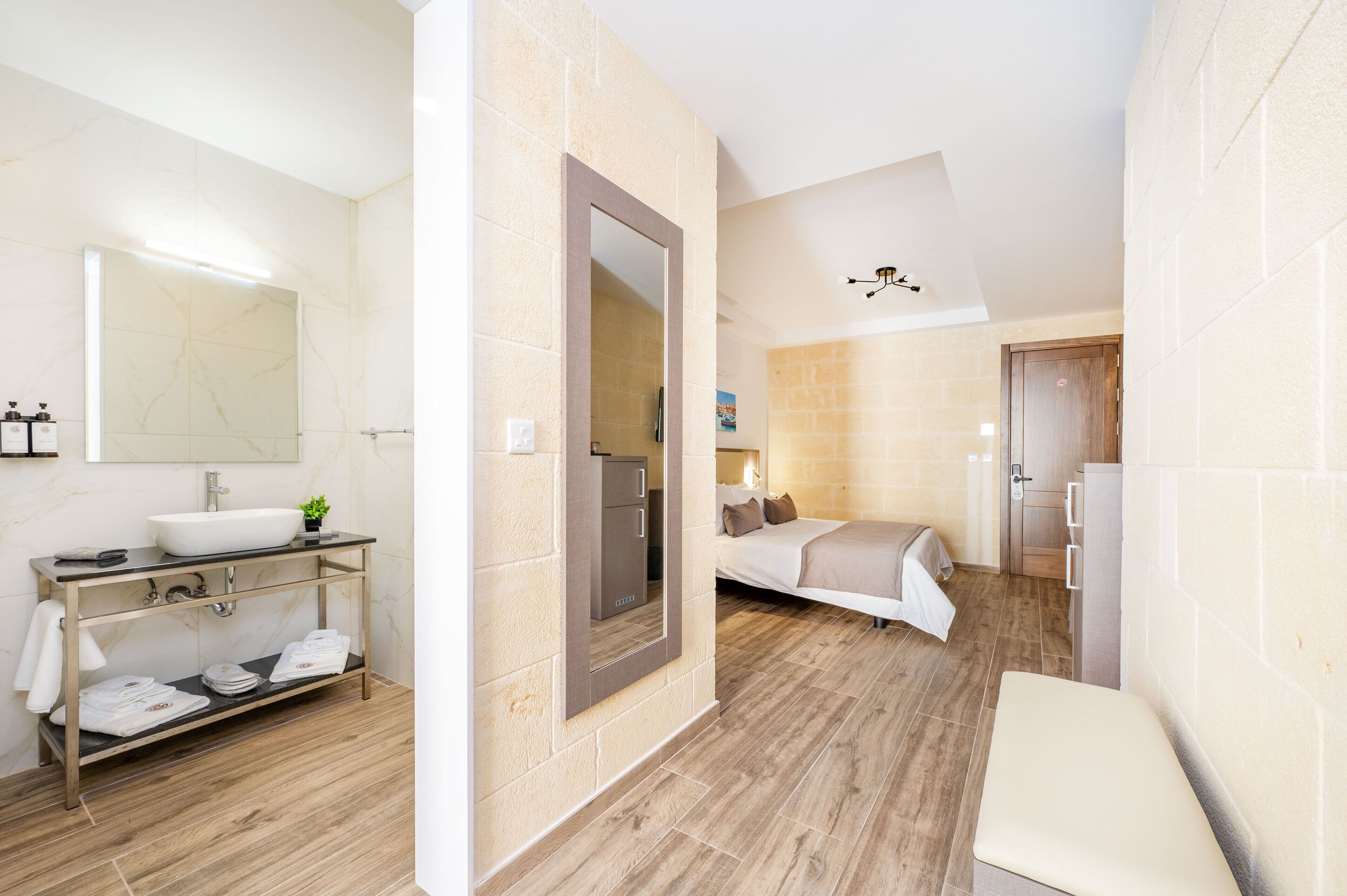 A modern bathroom with a marble sink, a vanity with towels, and a large mirror.