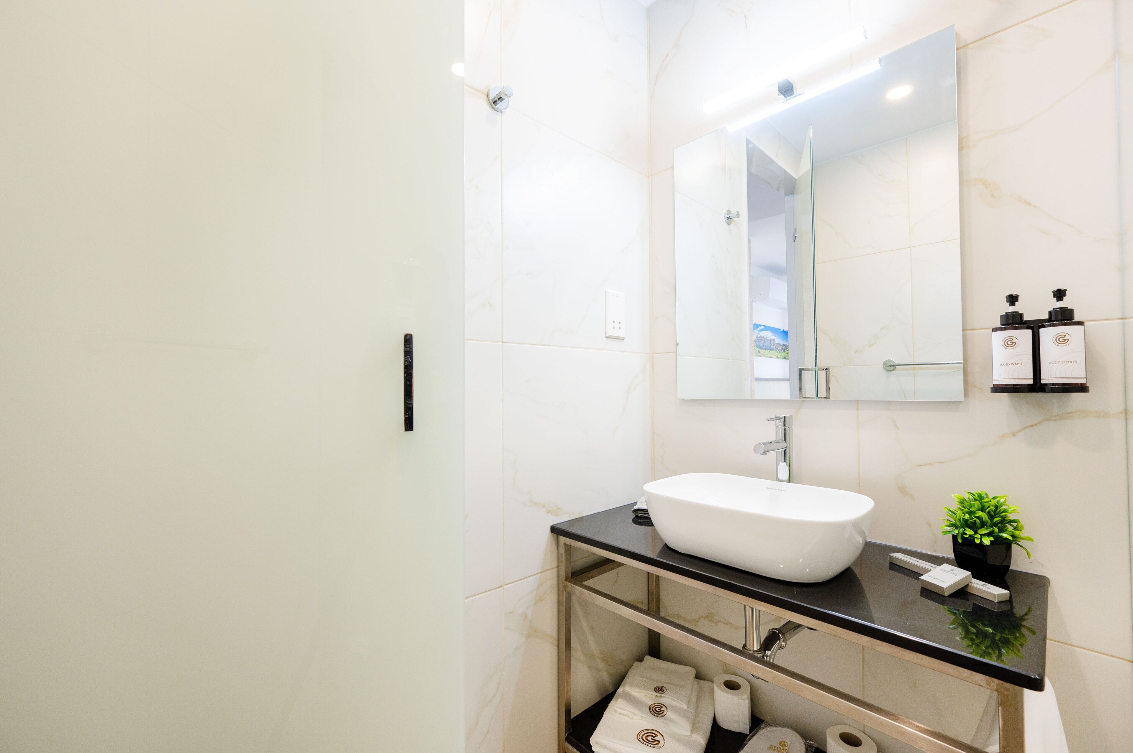A modern bathroom with a white sink, a large mirror, and a shower area.