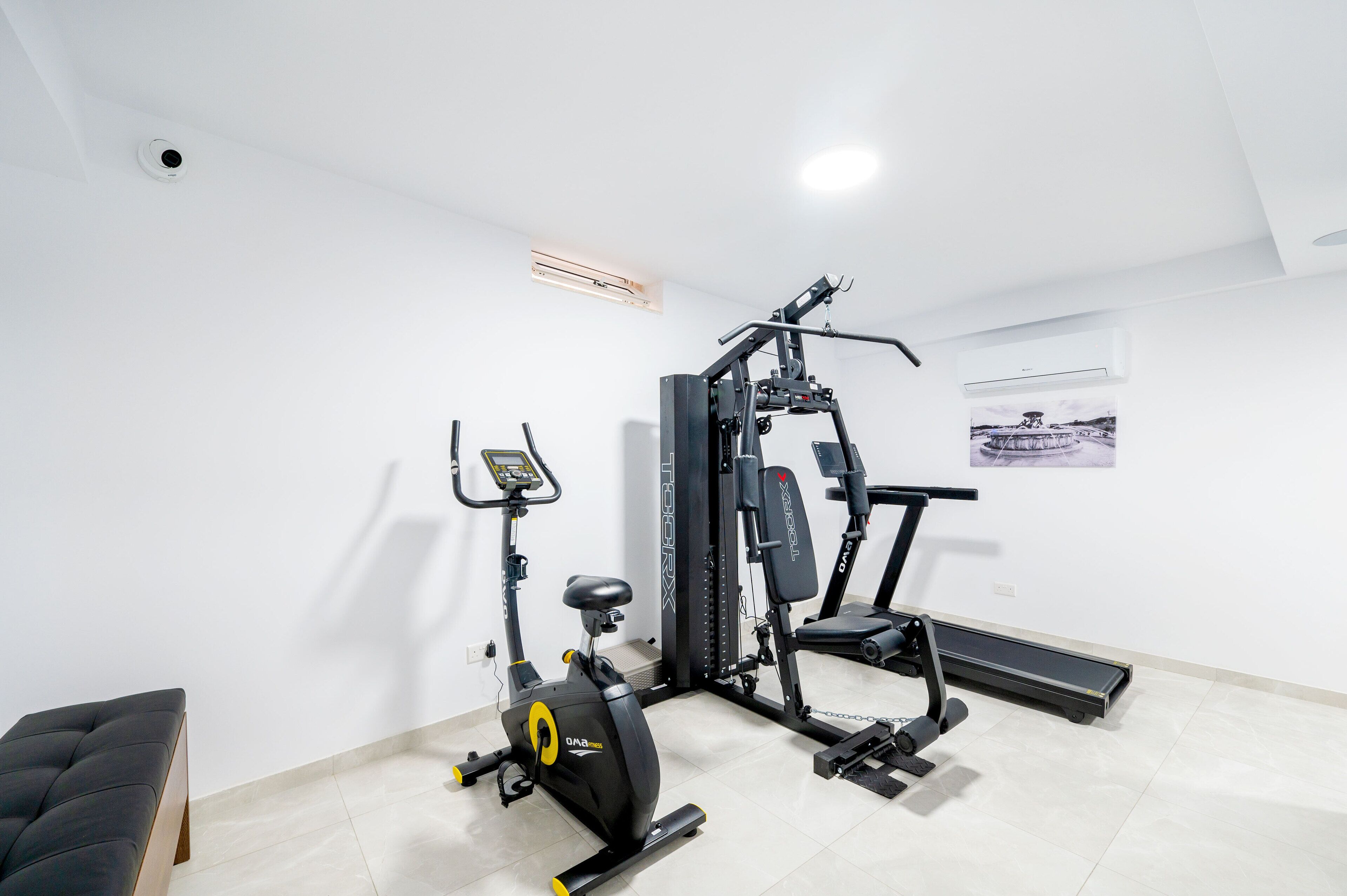 Un gimnasio en casa con una bicicleta estática, una cinta de correr y una máquina de pesas.