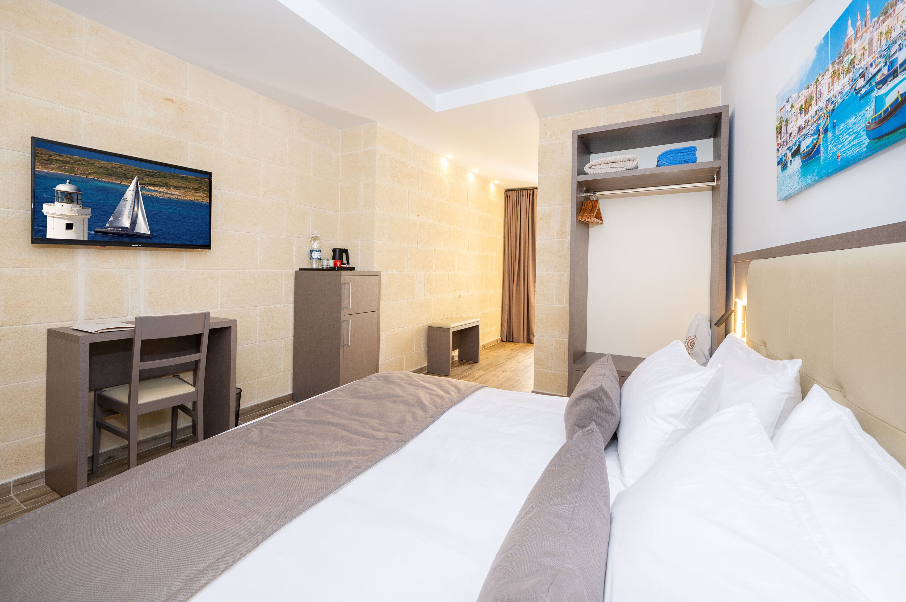 Ein Hotelzimmer mit Bett, Schreibtisch, Stuhl, Fernseher und einem Gemälde.