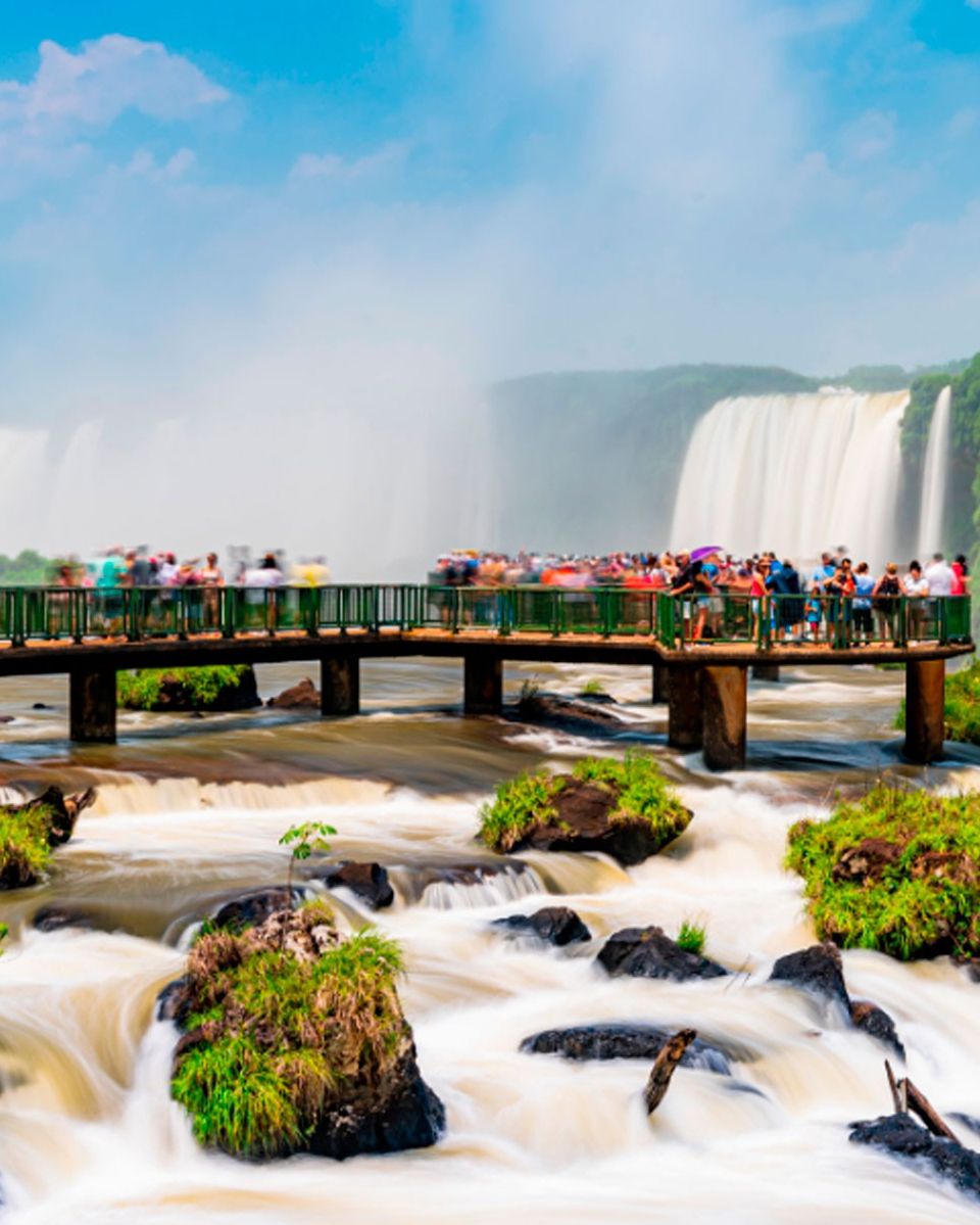Un puente con gente observando una cascada.