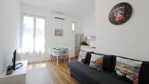 A modern living room with a grey sofa, white dining table, and a kitchen area in the background. - Casa Giotto (Scandicci)