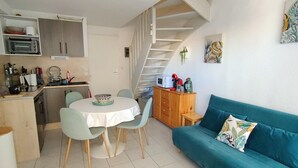 A compact living space with a kitchen, dining area, and a staircase leading to an upper level.