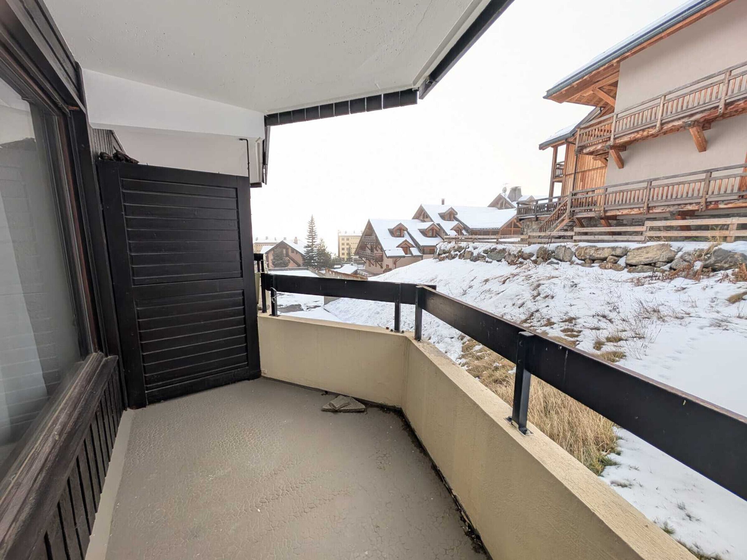 A balcony with a view of snow-covered buildings and a stone wall.