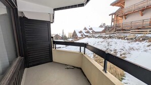 A balcony with a view of snow-covered buildings and a stone wall.