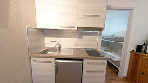 A compact kitchenette with a built-in dishwasher, a sink, and a small refrigerator.
