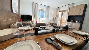 Un soggiorno moderno con zona pranzo, pareti in legno, televisore a schermo piatto e ampie finestre.