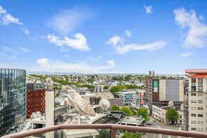 Une vue urbaine avec des bâtiments modernes, un ciel dégagé et une perspective lointaine sur un paysage verdoyant.