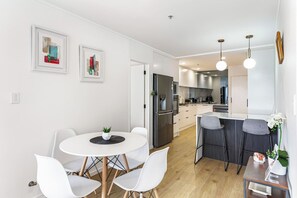 Eine moderne Küche mit weißen Schränken, einem eingebauten Backofen und einem Essbereich mit rundem Tisch und weißen Stühlen.