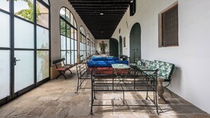 A corridor with a stone floor, large windows, and a blue sofa.