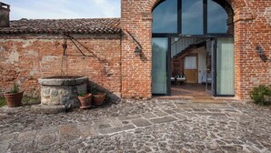 A rustic building with a brick exterior, a stone well, and a modern glass entrance.