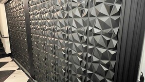 Un interno moderno con una parete a motivo geometrico e un cartello di avvertimento per una porta tagliafuoco a chiusura automatica.